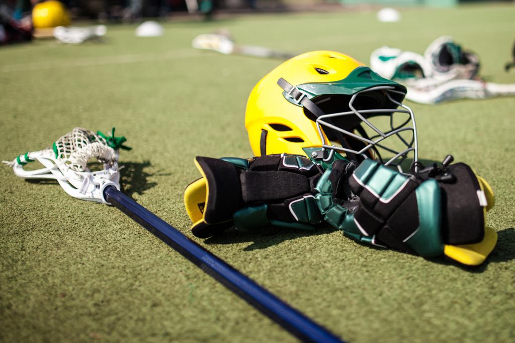 Casque, protections et crosse de lacrosse posés sur le terrain.